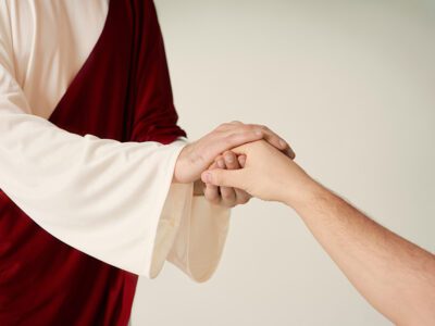 Jesus hand extended holding a mans hand